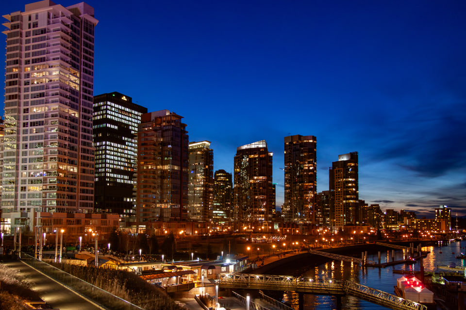Illuminated waterfront high-rises beneath a deep blue dusk sky.